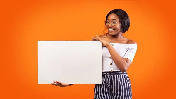 Millennial Girl Holding White Board Sorridente in piedi, sfondo arancione, Panorama — Foto Stock