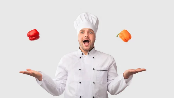 Cook Man malabarismo pimentas doces em pé sobre fundo branco — Fotografia de Stock