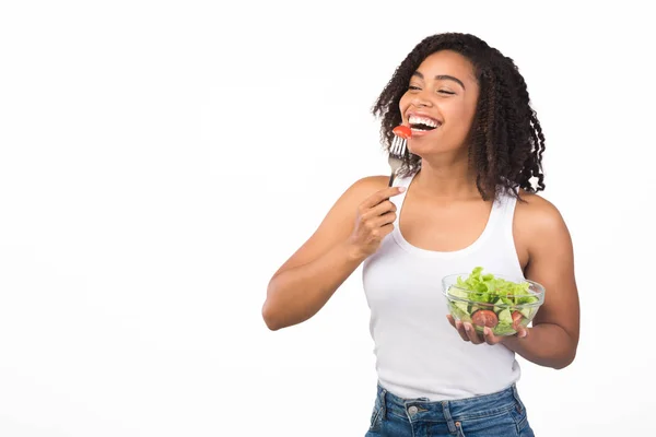 Alegre joven negro chica comer ensalada con tenedor — Foto de Stock