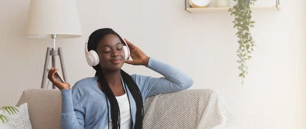 Sorrindo menina negra vestindo fones de ouvido sem fio, apreciando ouvir música de Smartphone — Fotografia de Stock