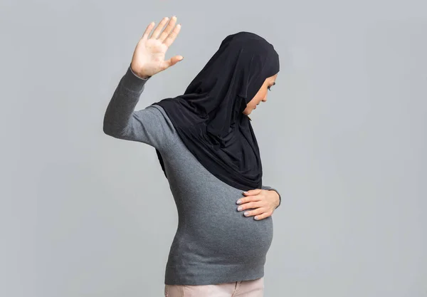 Налякана вагітна мусульманка в хіджабі робить стоп жест, ховаючись обличчям — стокове фото