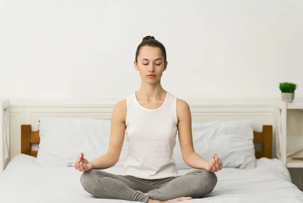 Meditation. Millennial woman sitting in lotus position on bed — Stock Photo, Image