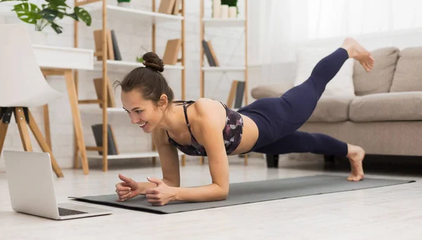 Fit mulher fazendo prancha de ioga e assistindo tutoriais on-line no laptop — Fotografia de Stock