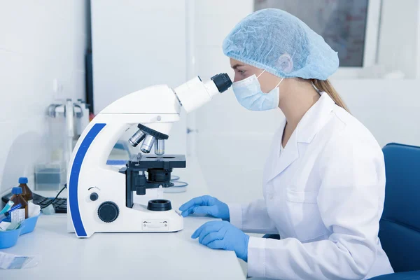 Mujer joven Trabajadora médica mirando al microscopio — Foto de Stock