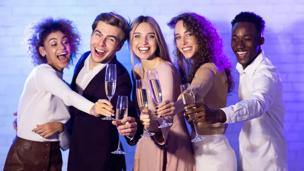 Amigos alegres Clinking Flautas de champanhe celebrando o Ano Novo em pé interior — Fotografia de Stock