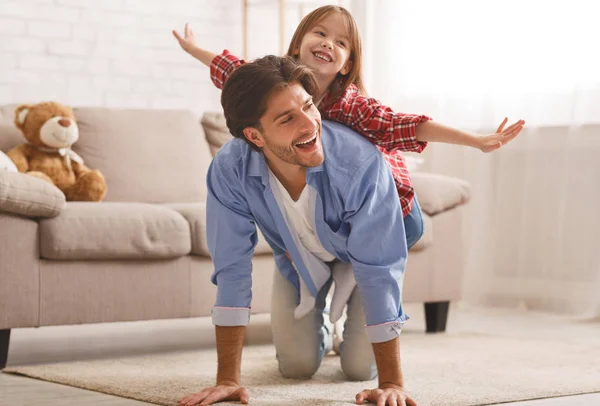 Filha sentada pai de volta, brincando juntos em casa — Fotografia de Stock