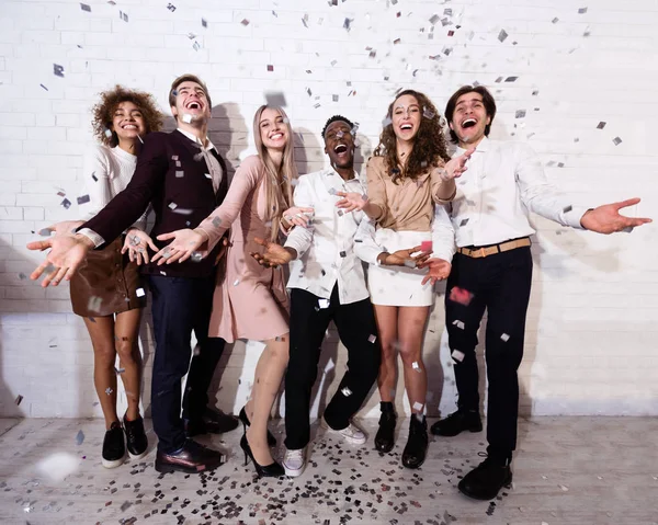 Millennials Standing Showered With Confetti Celebrating Against White Wall Indoor — Stock Photo, Image