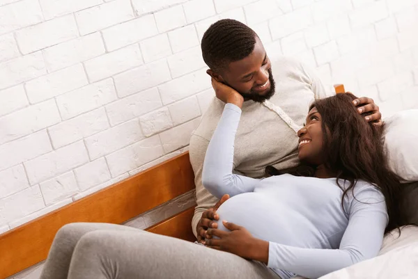 Jeune couple enceinte blottir dans le lit à la maison — Photo
