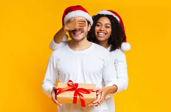 Afro ragazza coprendo gli occhi del suo fidanzato e dando regalo di Natale — Foto Stock