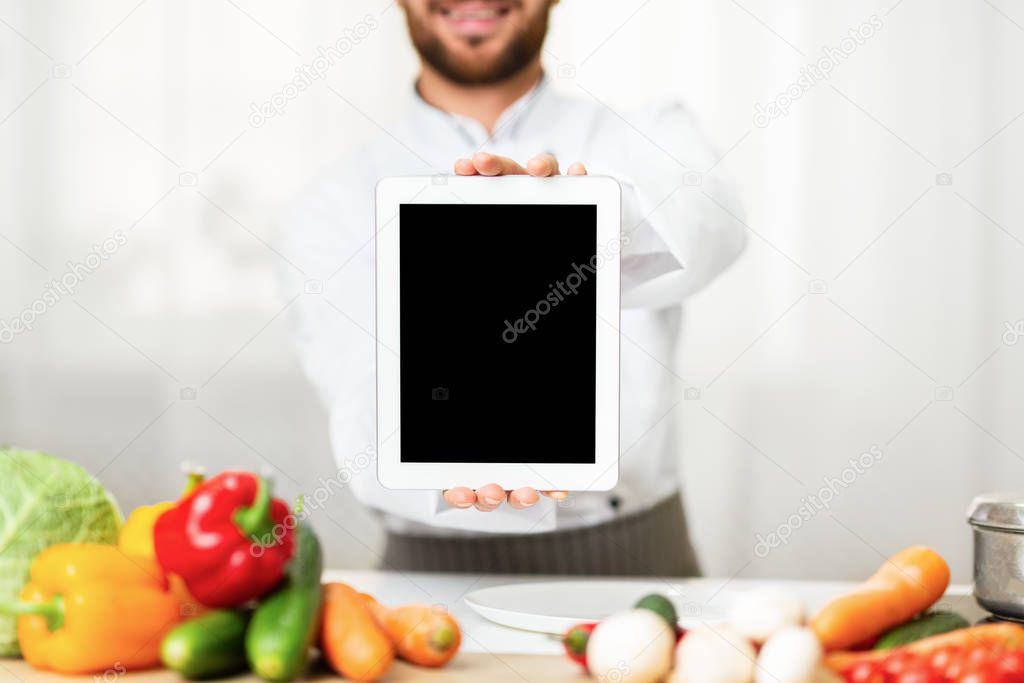 Chef Man Showing Tablet Screen Standing In Restaurant Kitchen, Cropped