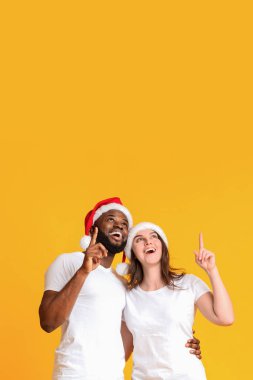 Noel Baba şapkalı heyecanlı çift fotokopi alanını işaret ediyor.