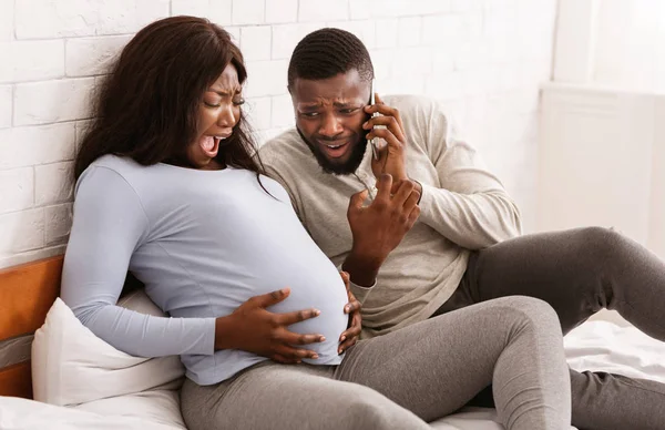 Mulher grávida sofrendo, marido chamando o médico de casa — Fotografia de Stock