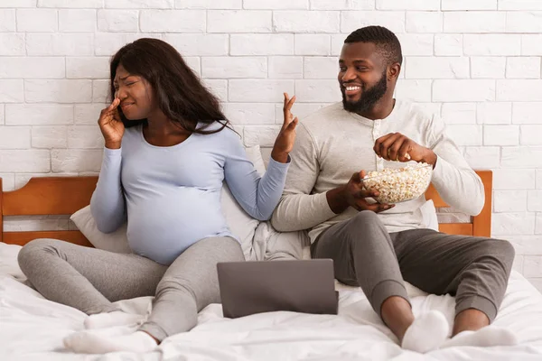 Hombre alegre comiendo palomitas de maíz mientras la mujer embarazada se aleja — Foto de Stock
