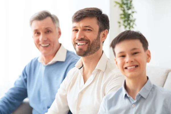 Happy Middle-Aged Man With Son And Elderly Father Sitting Indoor