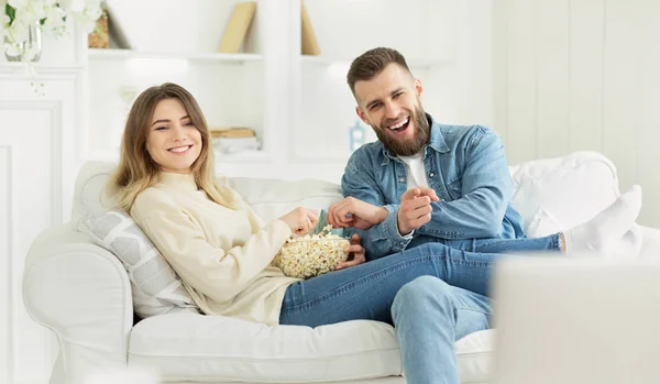 Счастливая пара тысячелетия смотрит телевизор с попкорном — стоковое фото