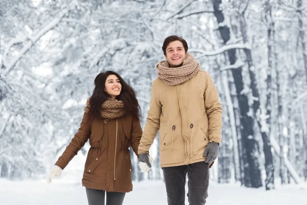 Usmívající se pár kráčející ruce v lese na vánoční ráno — Stock fotografie