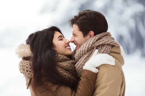 Carino amanti sfregamento loro naso abbracciare in piedi in neve parco — Foto Stock