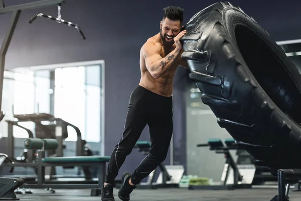 Muskulöser Mann trainiert im Fitnessstudio und dreht großen Reifen um — Stockfoto
