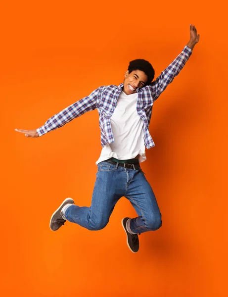 Überglücklicher Afro-Typ, der narrt und springt, oranger Hintergrund — Stockfoto