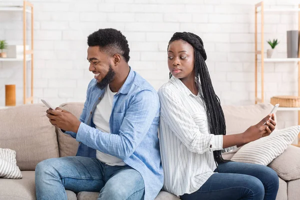 Schwarzes Mädchen blickt über die Schulter, wie ihr Freund mit jemandem SMS schreibt — Stockfoto