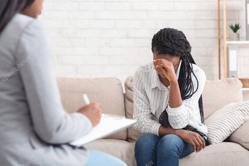 Depressed woman sitting on couch at psychotherapy session in coucellors office