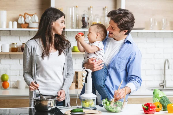 Веселі батьки готують обід з сином на кухні — стокове фото