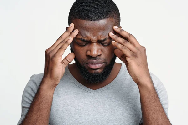 Negro chico teniendo dolor de cabeza, tocando su sienes — Foto de Stock