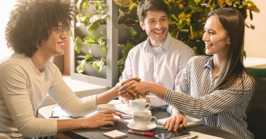 Kafedeki canlı toplantı sırasında yeni iş ortakları tokalaşıyor