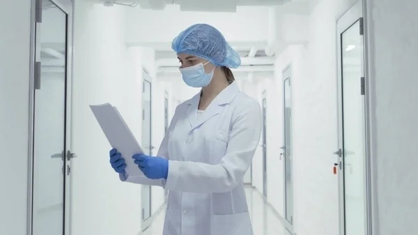 Ärztin in Schutzkleidung liest Krankengeschichte — Stockfoto