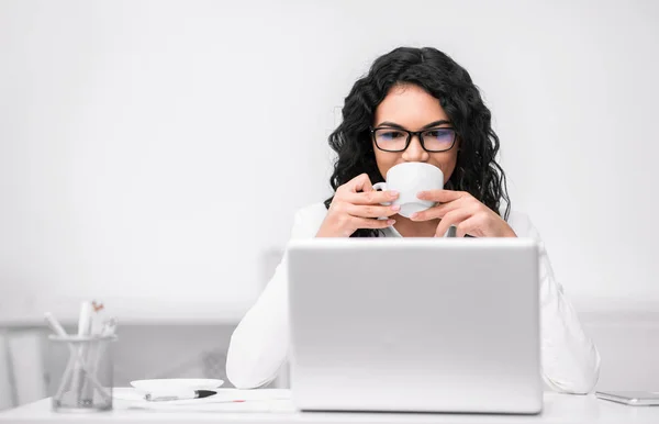 Femme latine buvant du café et regardant ordinateur portable — Photo