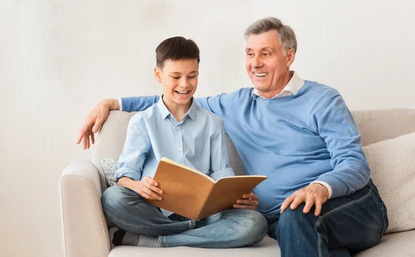 Niño leyendo libro favorito con el abuelo sentado en casa — Foto de Stock