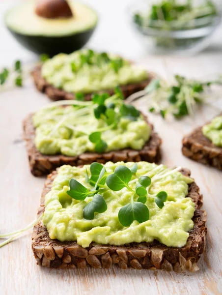 Trendy toasts with wholegrain bread, avocado and microgreens — Stock Photo, Image