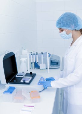 Genç bayan laboratuvar asistanı yüksek kaliteli ekipman ayarlıyor.