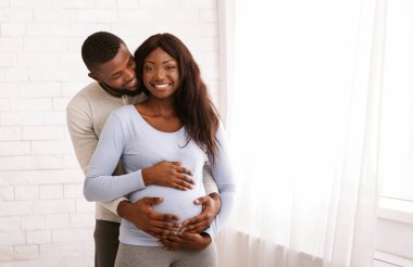 Aşık bir adam hamile karısına sarılıyor.