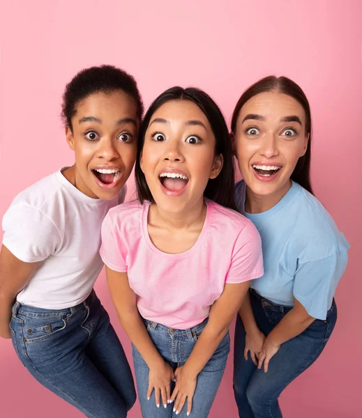 Trzy śmieszne dziewczyny patrzące na stojącą kamerę, różowe tło, wysoki kąt — Zdjęcie stockowe