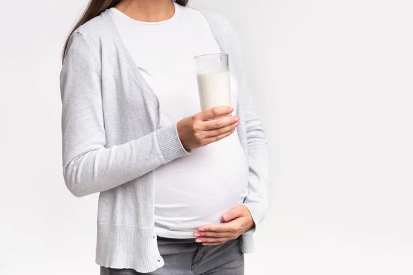 Nerozpoznatelný těhotná mladá žena drží sklo mléka, bílé pozadí — Stock fotografie