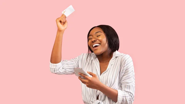 Joyful Girl Holding Smartphone en Credit Card over roze achtergrond — Stockfoto