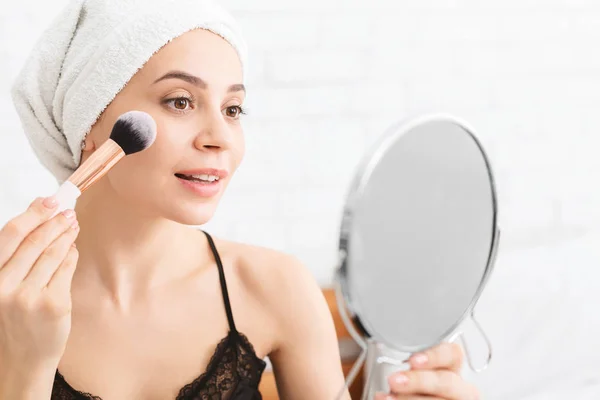 Young woman applying makeup, sitting after shower in bed — Stockfoto