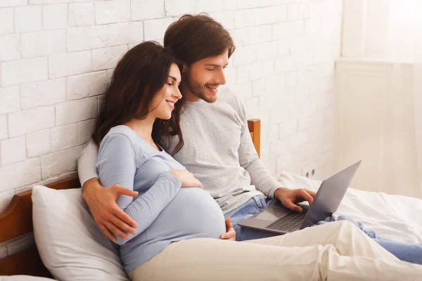 Παντρεμένο ζευγάρι περιμένει μωρό και βλέποντας ταινίες στο σπίτι με φορητό υπολογιστή — Φωτογραφία Αρχείου