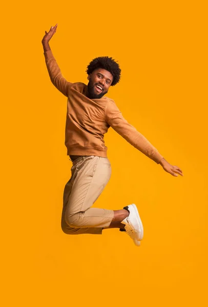 Turuncu arka planda zıplayan pozitif afro adam. — Stok fotoğraf