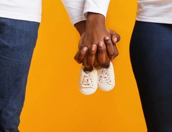 Cultivado de pareja negra sosteniendo botas de bebé juntas — Foto de Stock