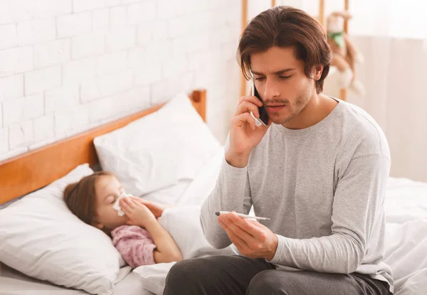 Father checking his daughters temperature, calling doctor — Stock Photo, Image