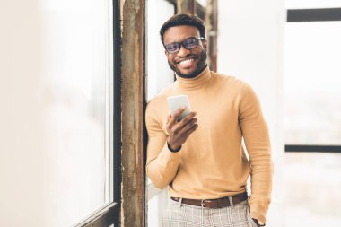 Ofisteki pencerenin yanında duran başarılı siyah adam.