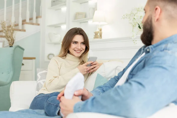 Young woman using phone, man giving feet massage to wife — Stock Photo, Image