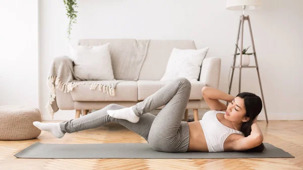 Home fitness. Girl doing abs crunches on floor