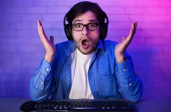 Bilgisayarda video oyunları oynayan kulaklıklı şaşırmış bir oyuncu — Stok fotoğraf
