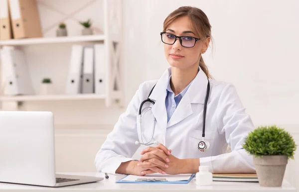 Lady Therapeut zit te kijken naar de camera in de moderne kliniek — Stockfoto