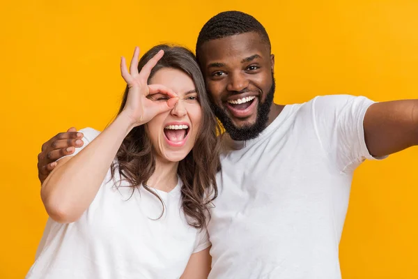 Alegre interracial casal tomando selfie, cara mostrando paz sinal — Fotografia de Stock