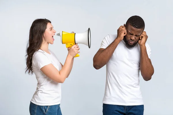 Irritierte junge Frau schreit mit Megafon ihren Mann an — Stockfoto