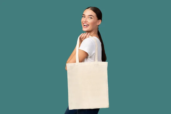 Mujer con bolsa blanca posando, fondo turquesa —  Fotos de Stock